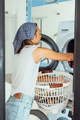 Young woman housekeeper sits in front of a washing machine. - PhotoDune Item for Sale