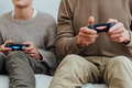 Cropped portrait of guys dad and teen son playing online game with joysticks. - PhotoDune Item for Sale