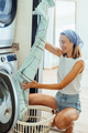Young woman housekeeper sits in front of a washing machine. Household chores. - PhotoDune Item for Sale