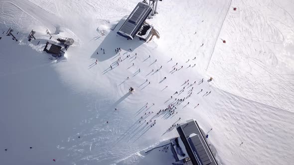 Aerial view of ski resort with people snowboarding down the hill. Stock footage. Flying over the ski