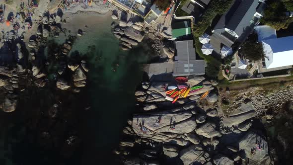 Birds eye drone shot of Bakoven beach in Camps Bay, Cape Town - drone is ascending over some stored