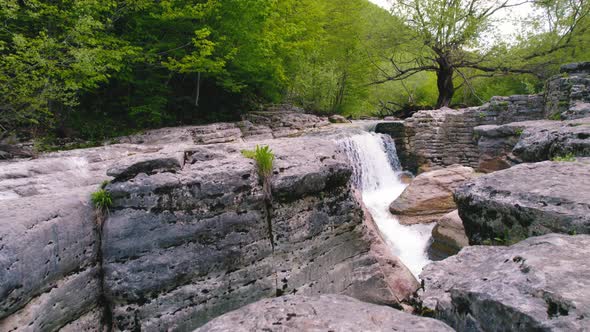 Top View of Rocky Mountain Ledges with a Small Waterfall Drone Shot