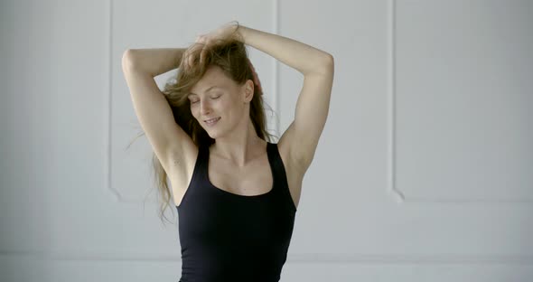 Carefree Young Woman Is Playing with Her Beautiful Light Brown Hair in Studio Room in Daytime