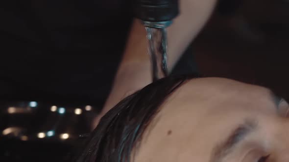 Young Man is Washed His Head in a Barber Shop a Closeup