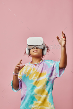 Modern schoolgirl in t-shirt and VR headset reaching to virtual object