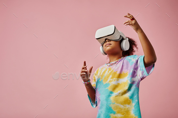 Cute girl in casualwear and VR headset standing in front of camera