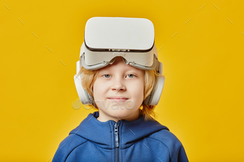 Cute blond boy with VR headset on forehead looking at camera