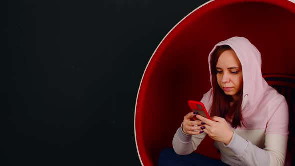 Woman Browsing Smartphone in Egg Armchair