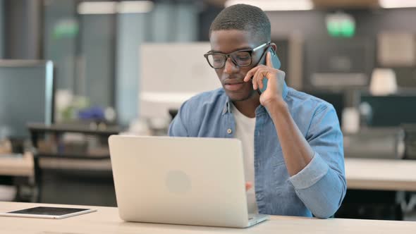 Young African American Man Talking on Phone at Work
