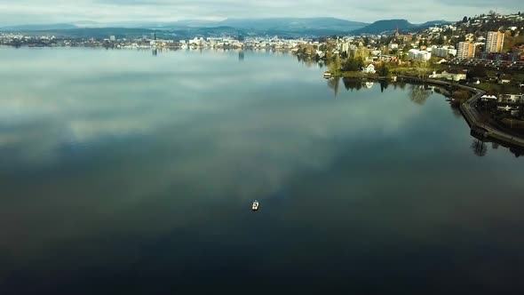 A boat is on the lake of Zug, behind is the city visible.