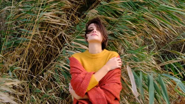 Hiker Woman Wearing Yellow Sweater Trekking in Cold Sunny Weather Hair Blowing in Wind