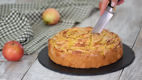 Cutting a piece of delicious apple cake with a knife.