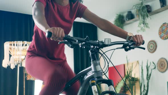 African Lady Is Working Out on an Exercycle at Home