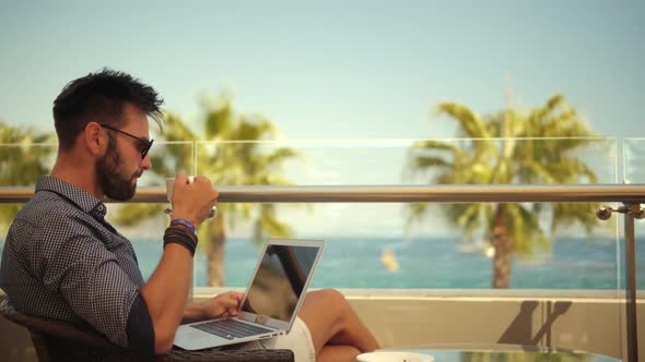 Businessman In Sunglasses. Businessman Drinking Tea On Vocation Resort. Man Sitting On Cafe At Sea.