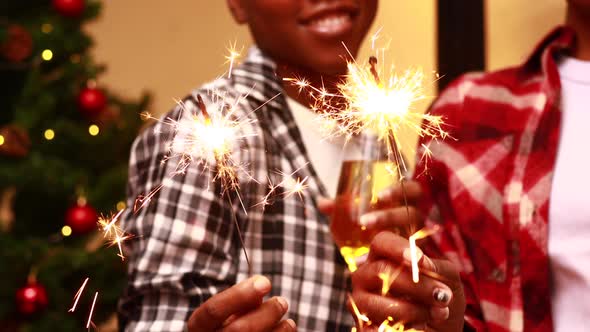 Close Up Hands of Mixed Race Women Holding Glass of Chapmange and Sparkles Indoors