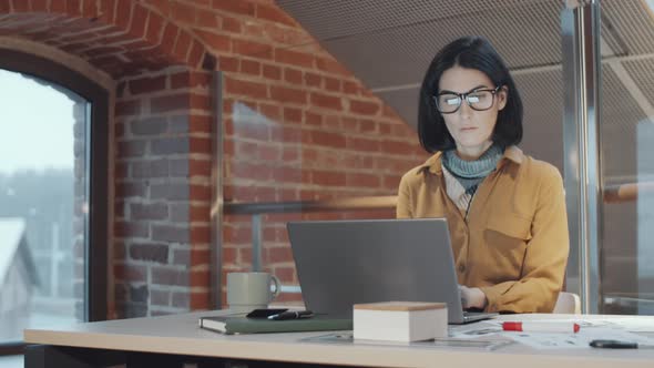 Brunette Female Designer Working on Laptop in Loft Office