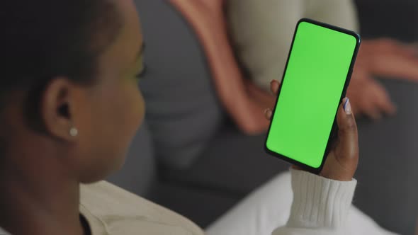 Back View of Woman Holding Smartphone with Green Screen