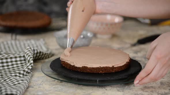 Pastry Chef Making A Cake On The Kitchen. Female Hand Squeezes The Chocolate Cream.	