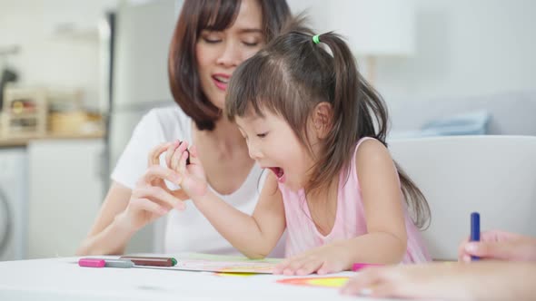 Asian young kid daughter coloring and painting on paper with parents. alt