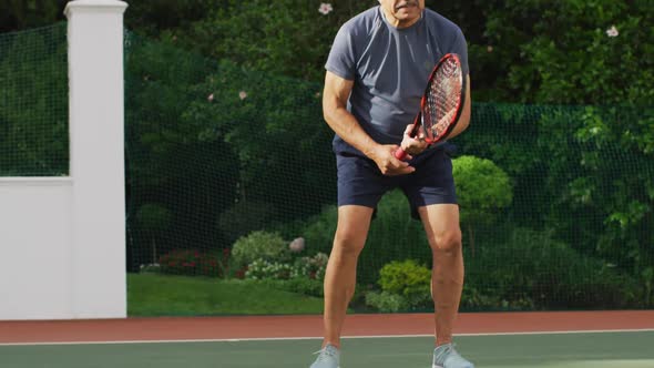 Video of focused of biracial senior man playing tennis on tennis court