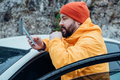 Bearded man using phone while resting stop on road trip. Autumn travel by car. - PhotoDune Item for Sale