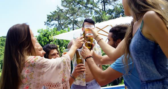 Group of happy friends toasting beer bottles and glasses at outdoors barbecue party