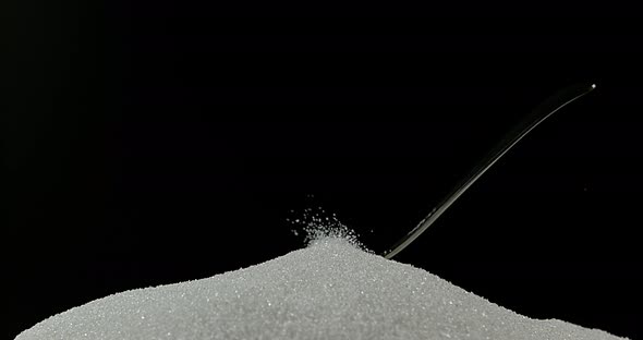 Spoon falling on Powder Sugar against Black Background, Slow Motion 4K
