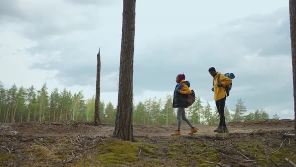 Two Africanamerican Travel Hikers with Backpack Walking While Looking the Landscape in the Forest