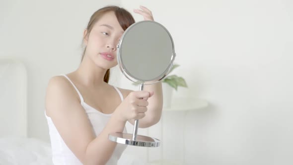 Beauty young asian woman smiling look at mirror of checking skin care caucasian with wellness.