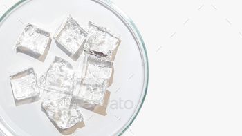 Top view of transparent frozen gel cubes on petri dish on white background