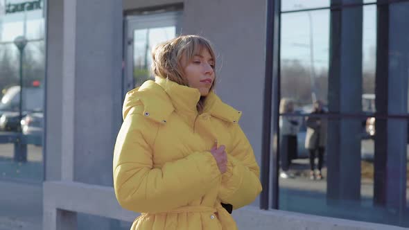 Young Blonde Walking in City Wearing Stylish Yellow Coat in Autumn