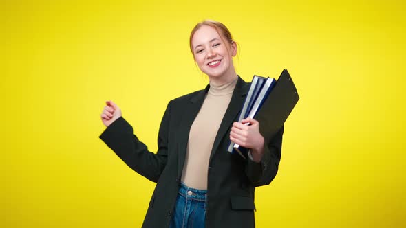 Cheerful Confident Female CEO with Toothy Smile Dancing with Documents at Yellow Background