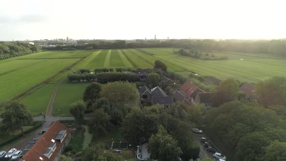 Aerial of a Small Dutch Town during Sunset with Green Countryside in the Background and Trees