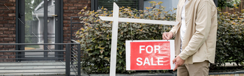 cropped view of property realtor hanging for sale signboard near contemporary city house, banner