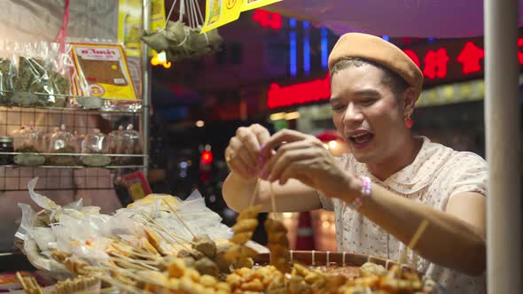 4K Portrait of Asian lgbtq guy with woman walking in the city with eating street food night.