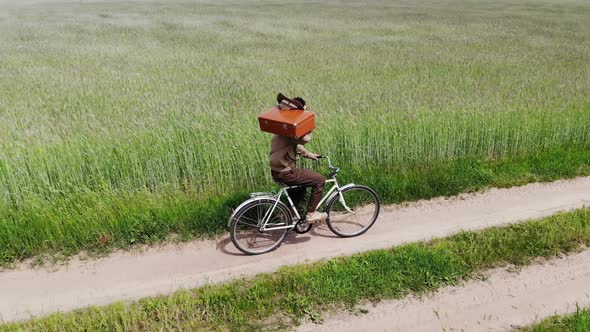 Man Alone Walking By Country Road in a Green Field Holding Suitcase in a Hand Funny Travel Concept