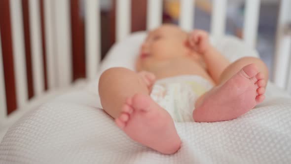 Cute Legs and Heels of a Newborn Baby Closeup Lying in a Crib in a Cocoon for a Newborn