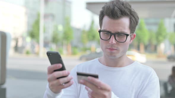 Young Man Reacting to Online Payment Failure on Smartphone Outdoor