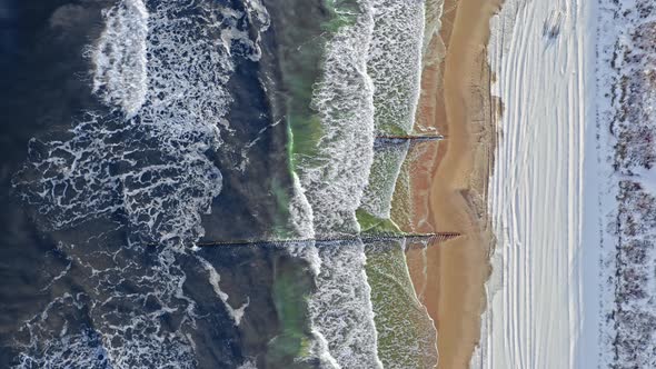 Waves on Baltic sea and snowy beach in winter.