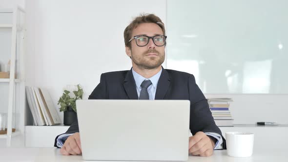 Thinking and Smiling Businessman Sitting in Office