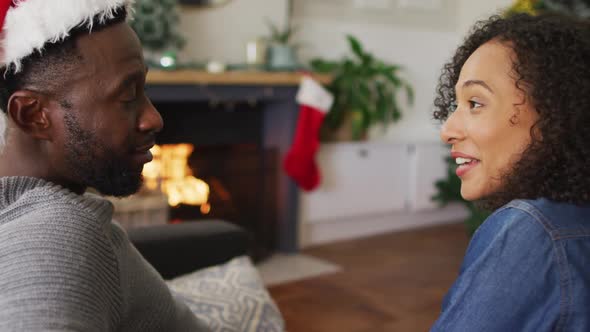 Happy african american couple sitting on sofa at fireplace and talking