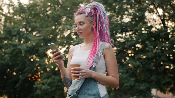Pretty Student with Colored Hair Using Smartphone Holding Coffee Outdoors