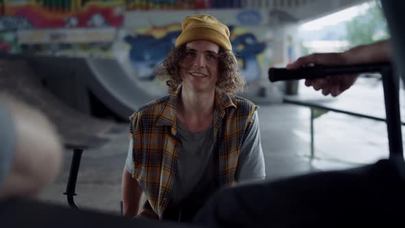 Smiling Friends Enjoying Conversation Together at Skate Park Graffiti Wall