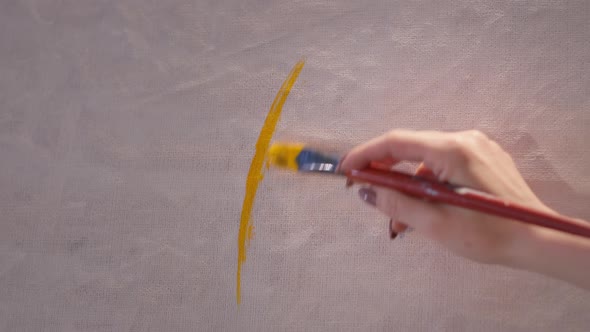 Art Hand with Yellow Paint on Brush Draws a Modern Picture on Large Canvas Closeup Artist During the