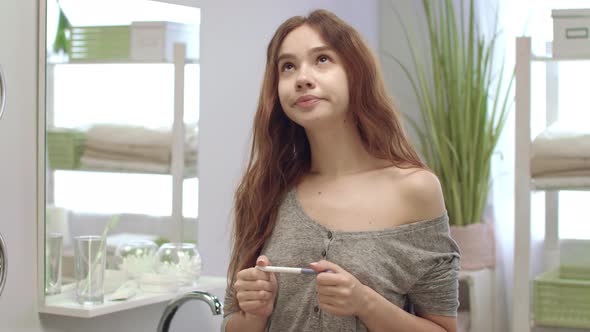 Young Woman Holding Pregnant Test and Waiting Results in Bath Room Interior