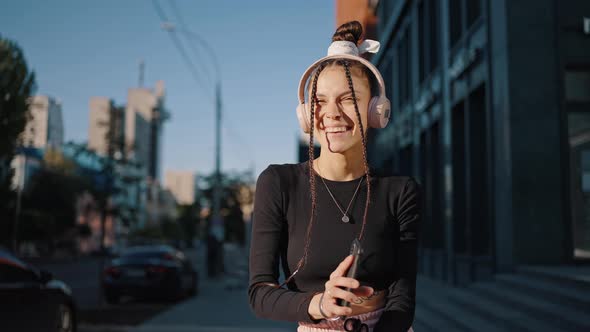 Young Woman in Black Blouse Dances to Music on Smartphone