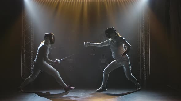 Side View Duel of Two Women Fencers. Sportswomen Practice Strikes, Attack and Defend. Filmed Indoors