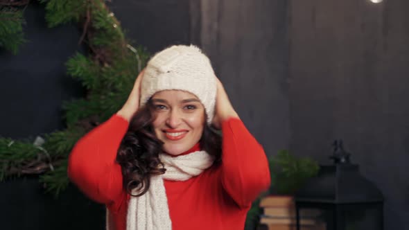 Lady putting on white knitted hat.