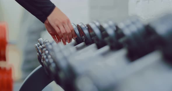 Metal Dumbbells Lie in a Row on a Rack in the Gym