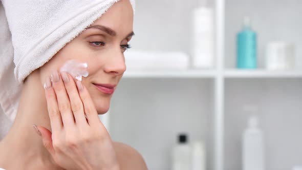 Adorable Female Applying Cosmetic Hydration Cream on Face